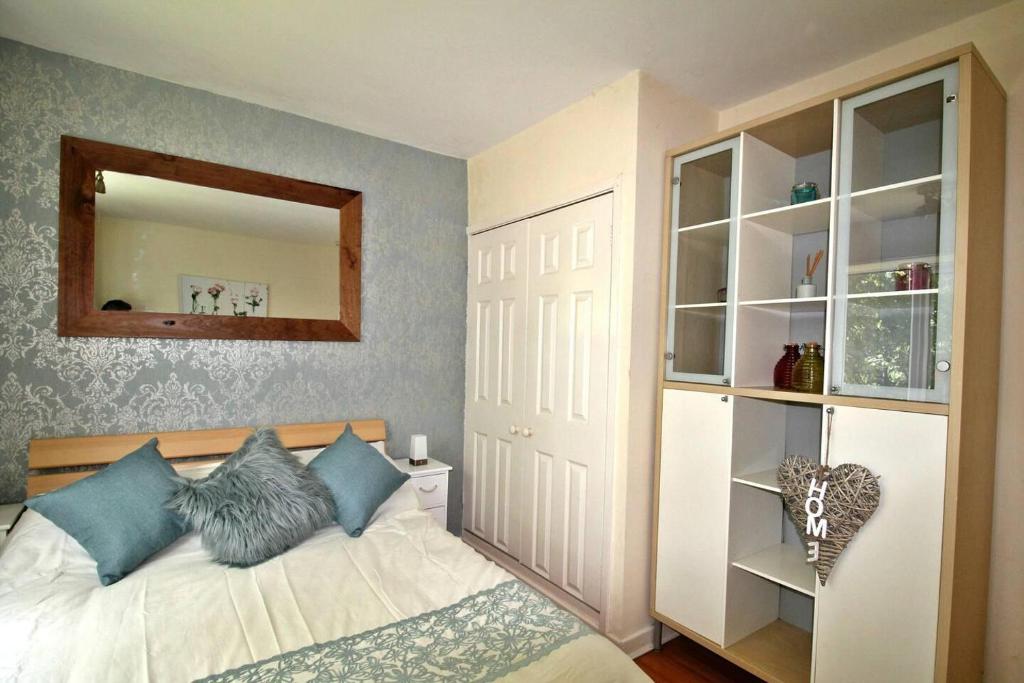 a bedroom with a bed with blue pillows and a mirror at Boswell-Large Balcony Apartment-Town & Racecourse in Doncaster