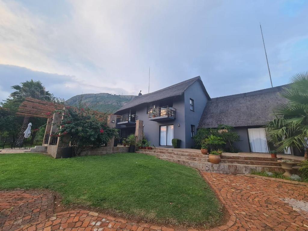 a house with a grass yard and a building at Mountain Villa House in Hartbeespoort