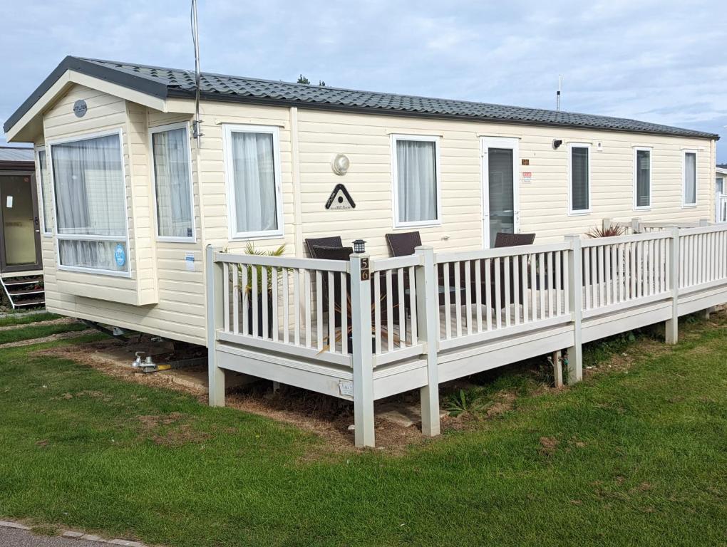 uma casa móvel branca com uma cerca branca em Beachhome em Heacham