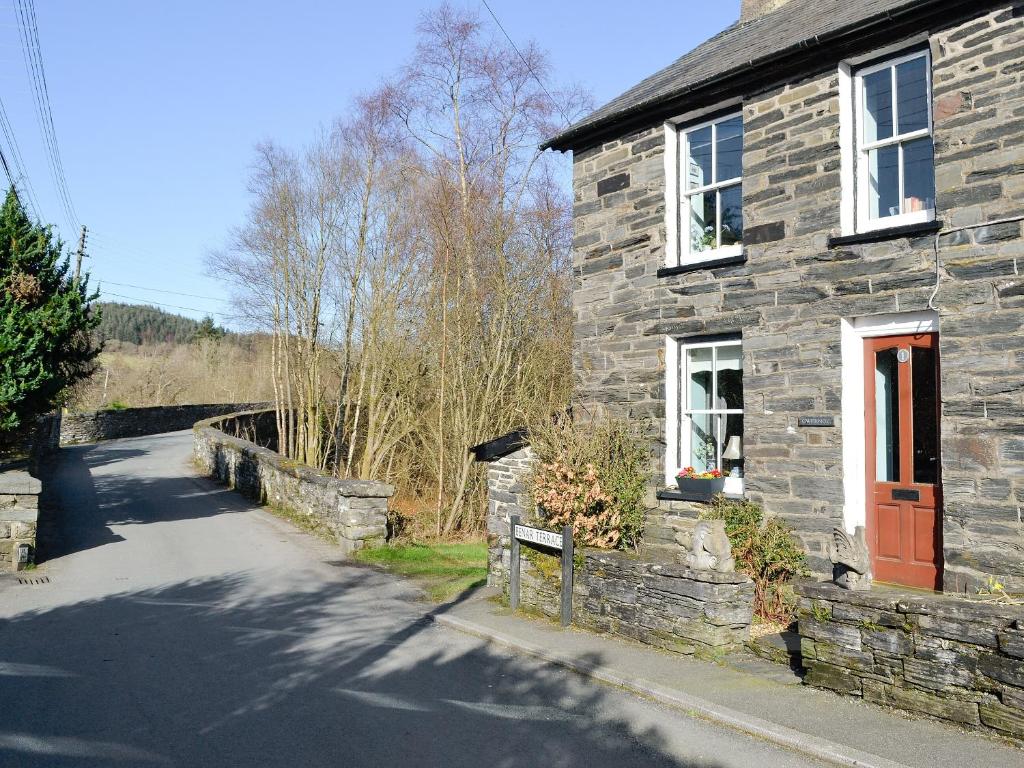 a stone house with a red door on a road at Gwernol in Dolwyddelan