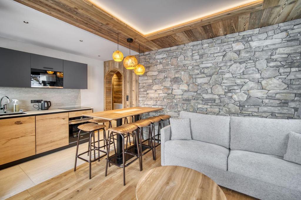 a kitchen with a couch and a stone wall at Appartement Cafetan in Tignes