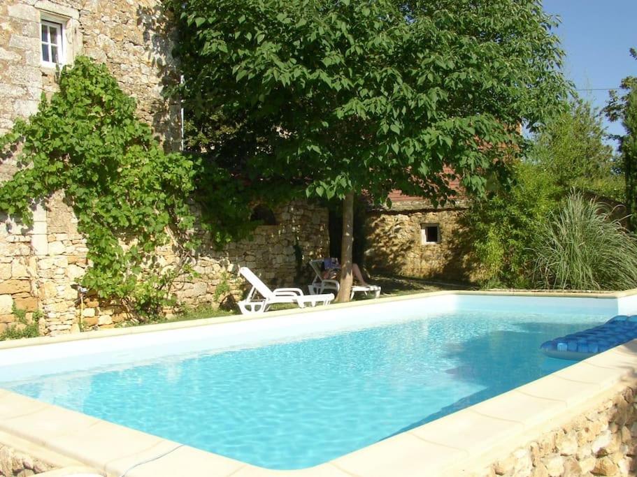 basen przed kamiennym budynkiem w obiekcie Landhaus mit Pool Petite Mombette w mieście Cénac-et-Saint-Julien