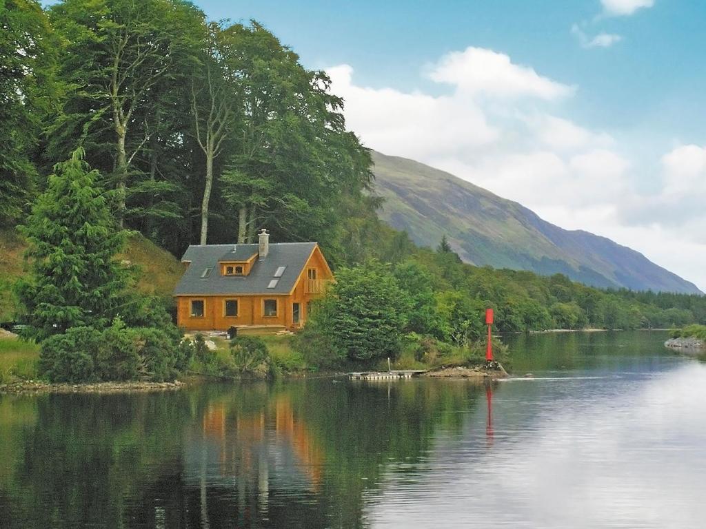 a house sitting on the side of a lake at Gairlochy Bay in Gairlochy