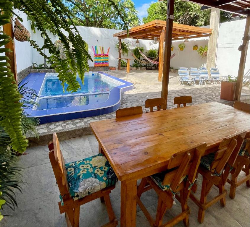 a wooden table and chairs next to a swimming pool at Vivir La Costa - Casa de Fina in Ríohacha