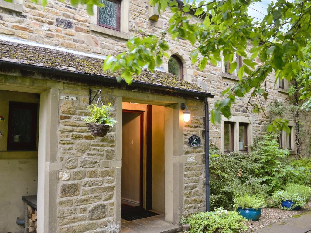 a stone house with a door and a plant at Fell View in Kettlewell