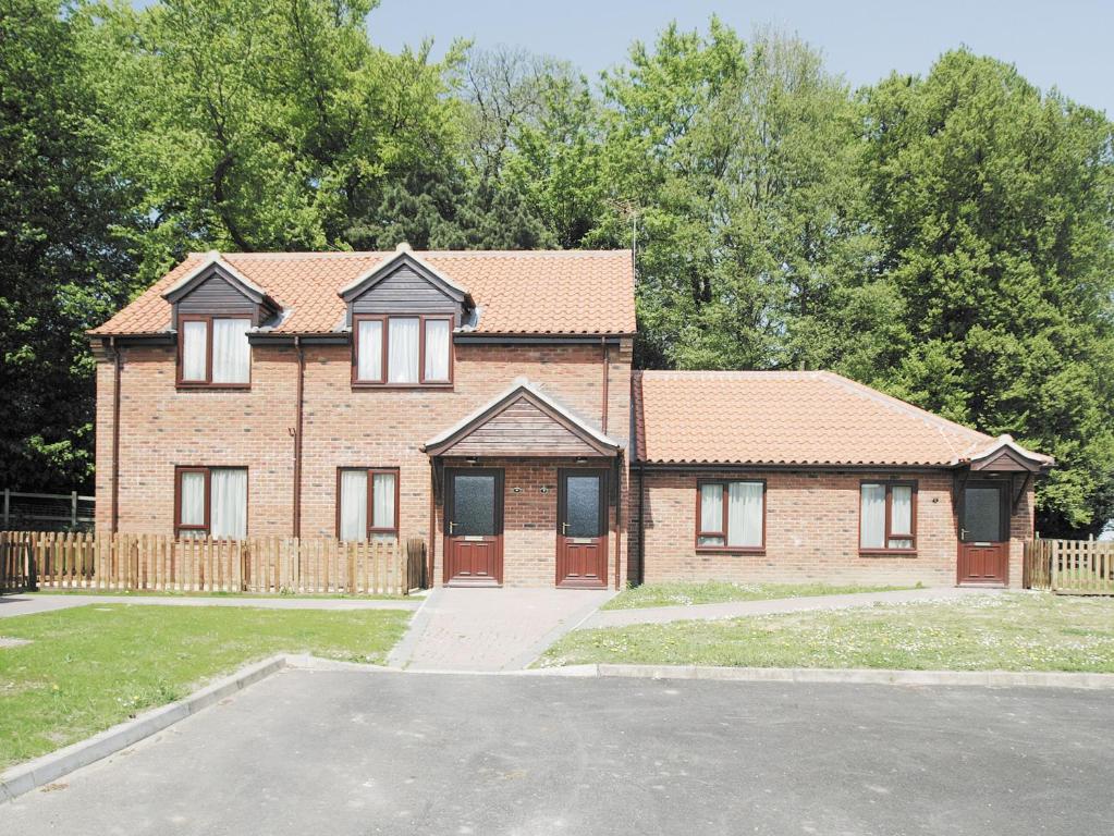 a brick house with a fence and a driveway at Barley Cottage - W40837 in Horsford