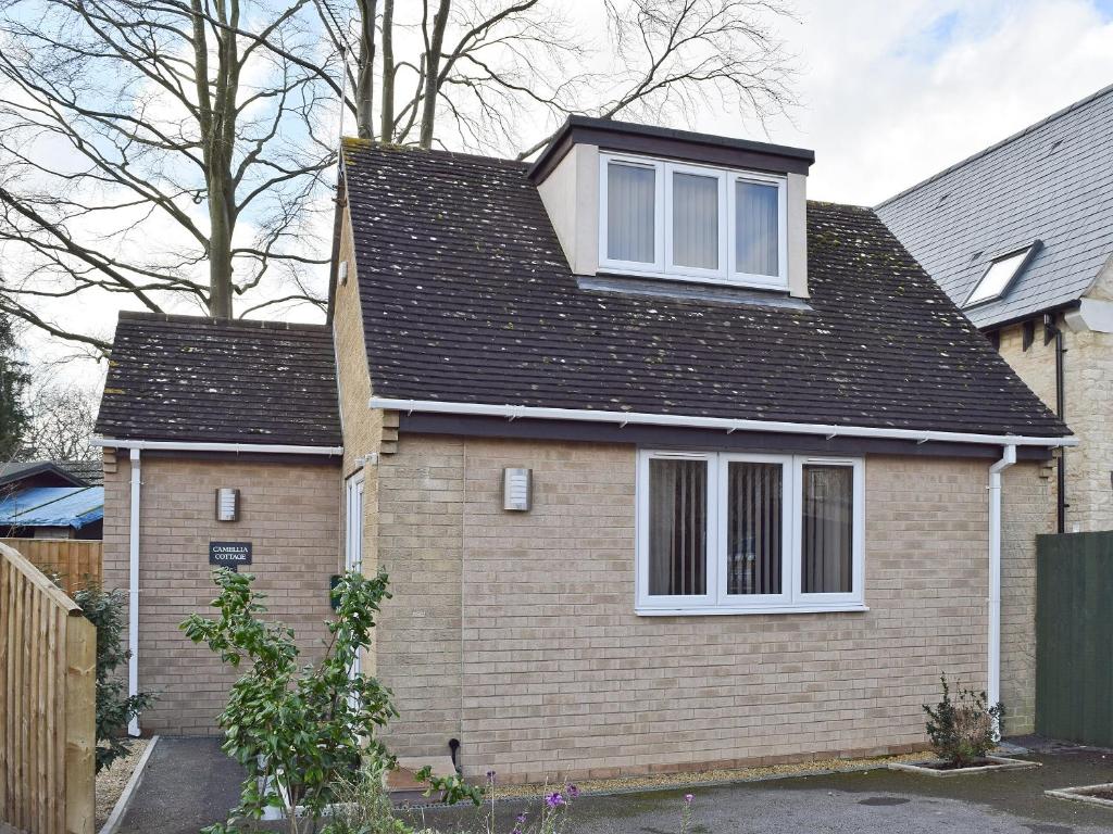 a house with a black roof and white windows at Camelia Cottage in Witney