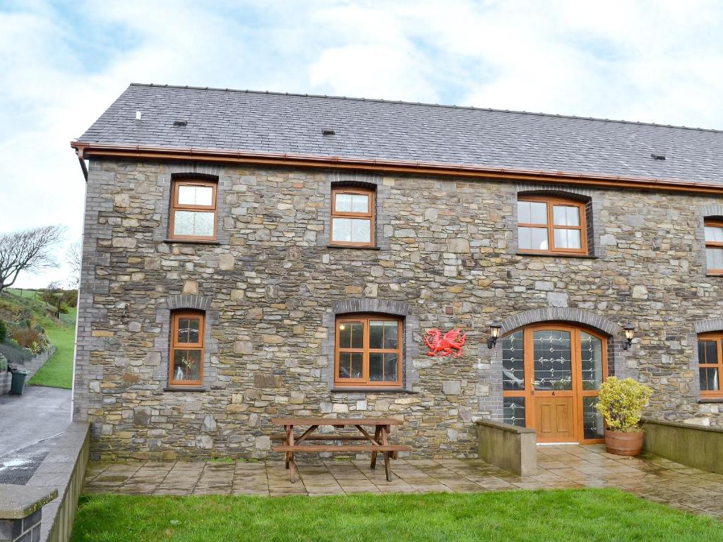 a stone house with a picnic table in front of it at 4 Pengraig Draw in Llanychaiarn