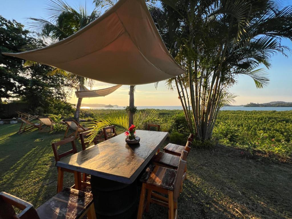 a wooden table and chairs with a view of the ocean at Corto Novo Maison d'hôtes-Camping in Nosy Be