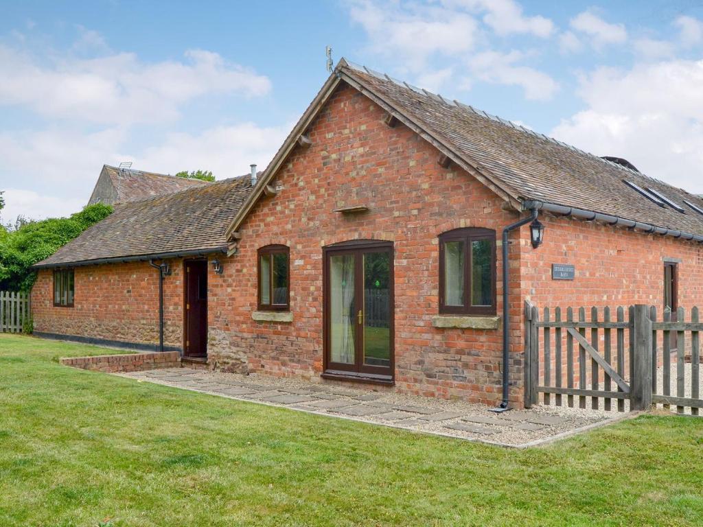 a red brick house with a wooden fence at Skimblescott Barn in Monkhopton