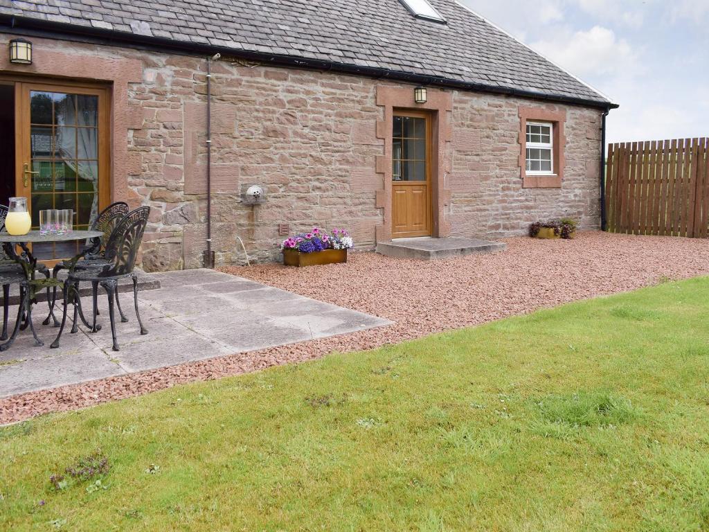 a patio with a table and chairs in front of a building at The Stables - Uk5532 in Kepculloch