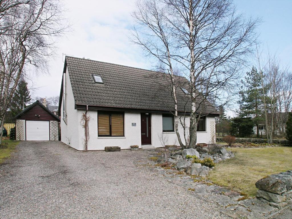 Uma casa branca com uma entrada à frente. em Rowan Cottage em Carrbridge