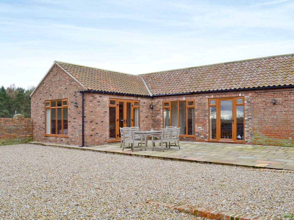 a brick house with a table and chairs on a patio at Haddocks Nook in Aldwark