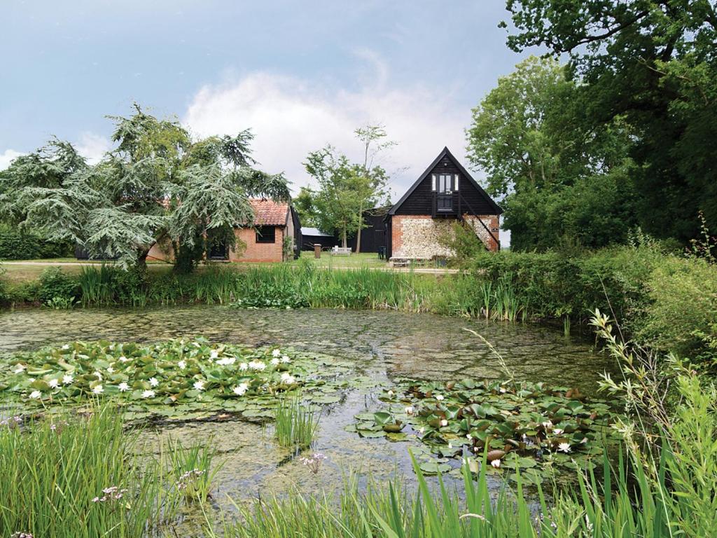 a pond with lily pads in front of a house at The Stables - E3491 in Saxtead