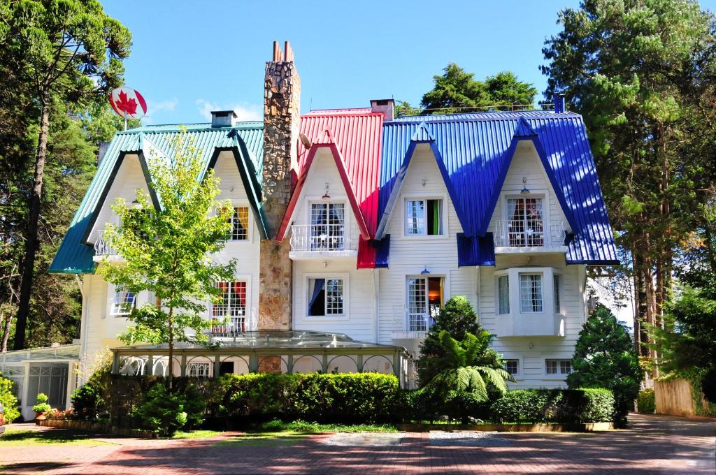 a large white house with a colorful roof at Canada Lodge Campos do Jordão in Campos do Jordão