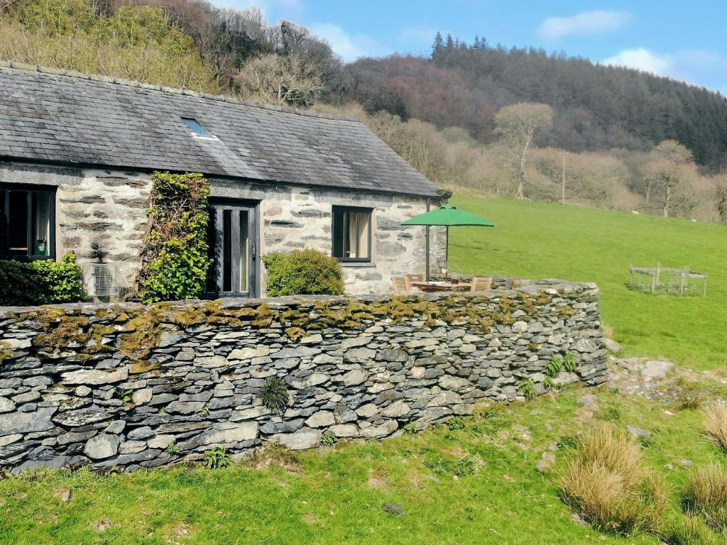 a stone house with a stone wall and an umbrella at 3 Benar in Penmachno