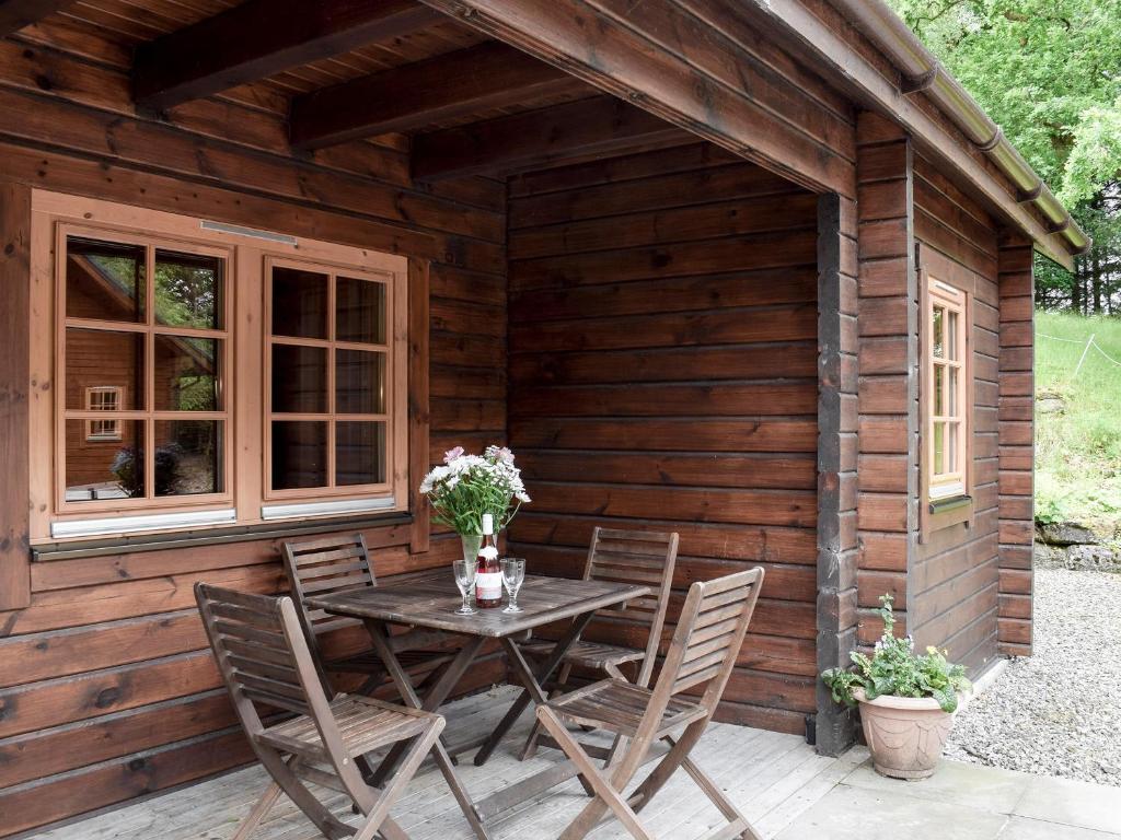 a wooden cabin with a table and chairs outside at Alder - Uk5502 in Killin