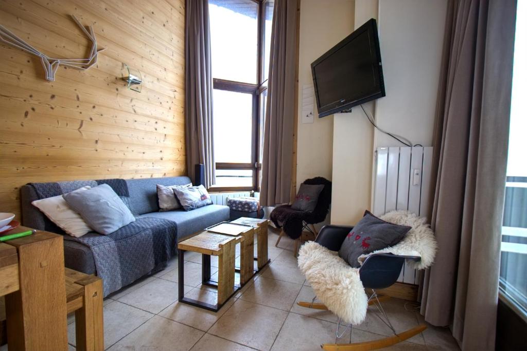 sala de estar con sofá azul y TV en Tignes - Duplex spacieux à 2 mn des pistes - 10 pers en Tignes