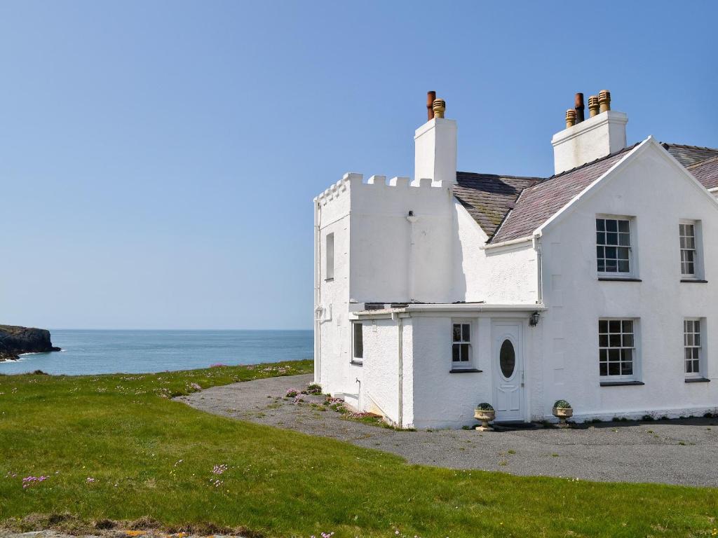 een oud wit huis aan de kust van de oceaan bij Bwthyn Y Borth in Rhoscolyn