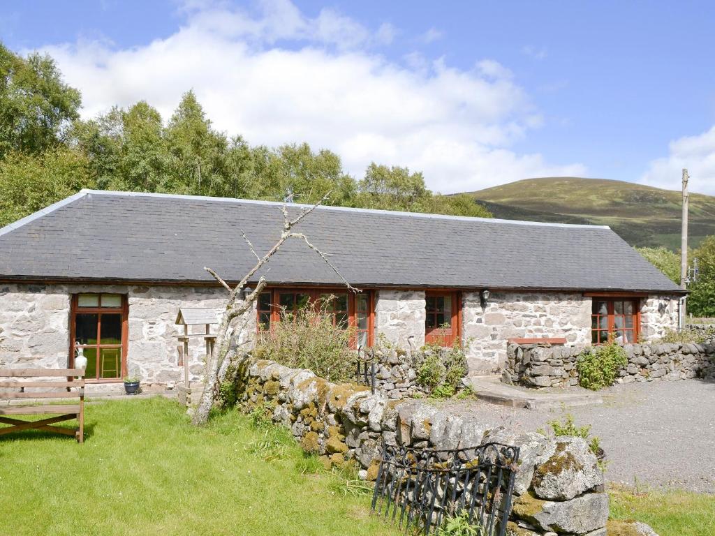 a stone cottage with a stone wall and a building at Rowan Tree Cottage - S4216 in Tulchan