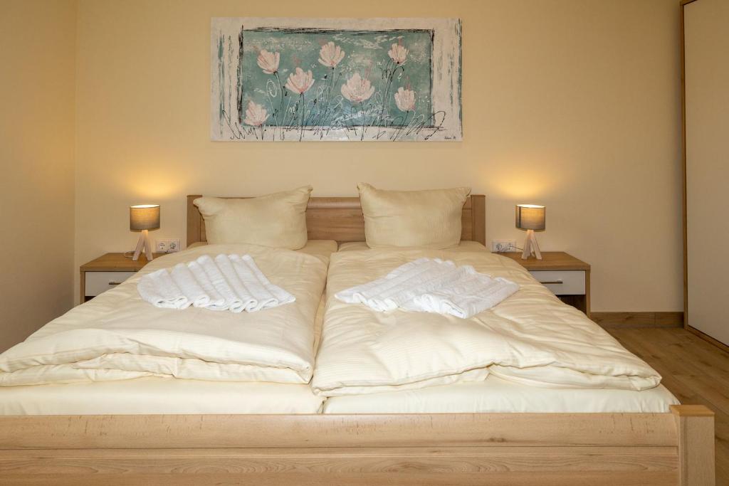 a large bed with white sheets and pillows on it at Seewohnung "Rügen" in Gützkow