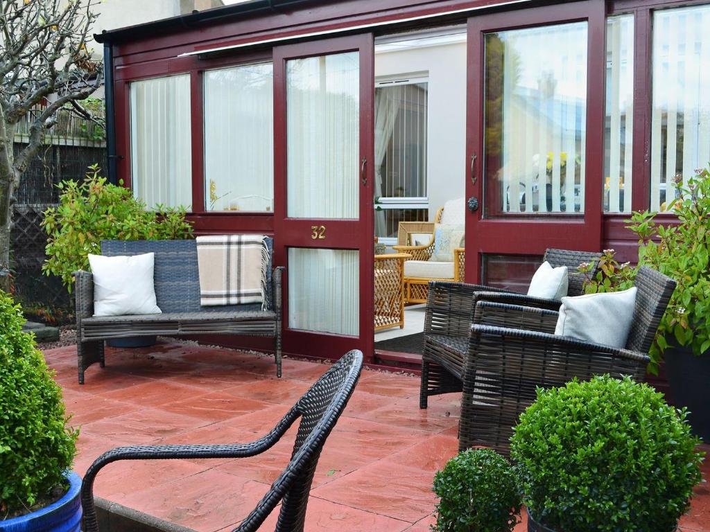 a patio with wicker chairs and a house at Rose Cottage in Norham