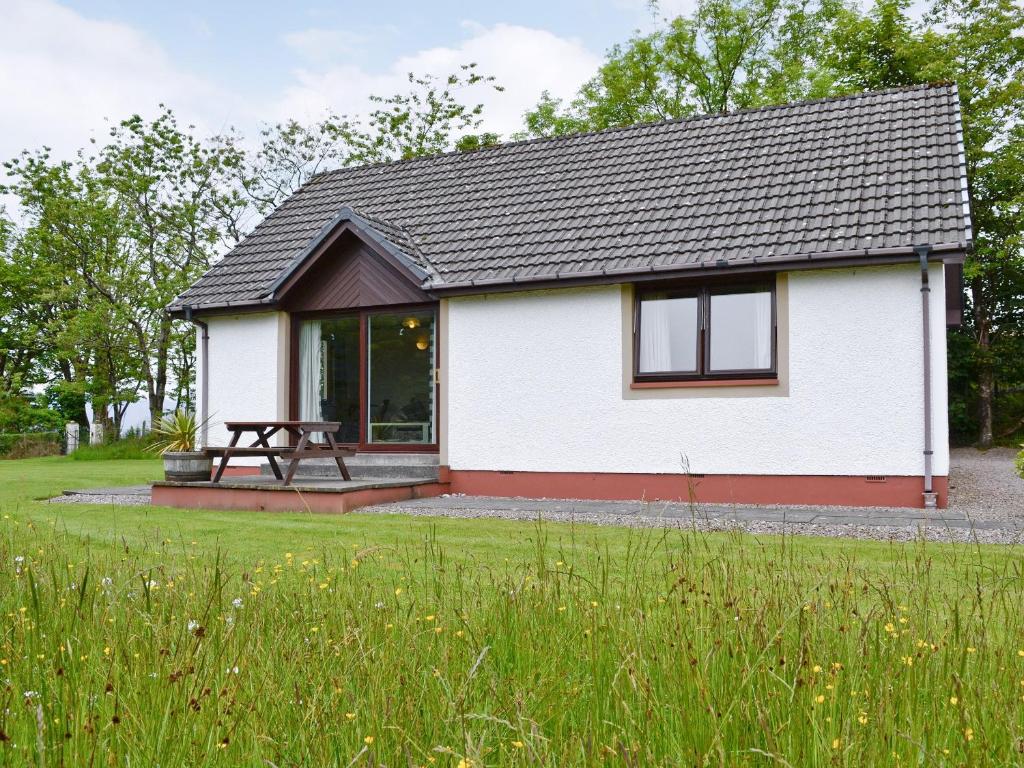 a small white house with a picnic table in a field at Duart in Onich