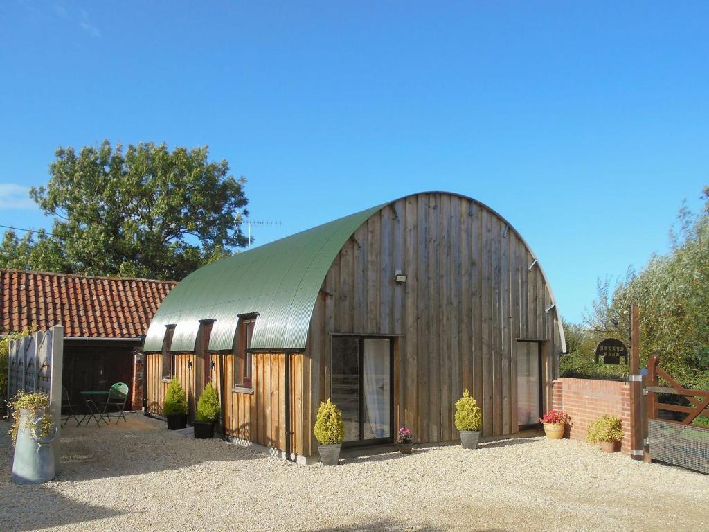 een grote houten schuur met een groen dak bij Hollys Barn in Brent Knoll