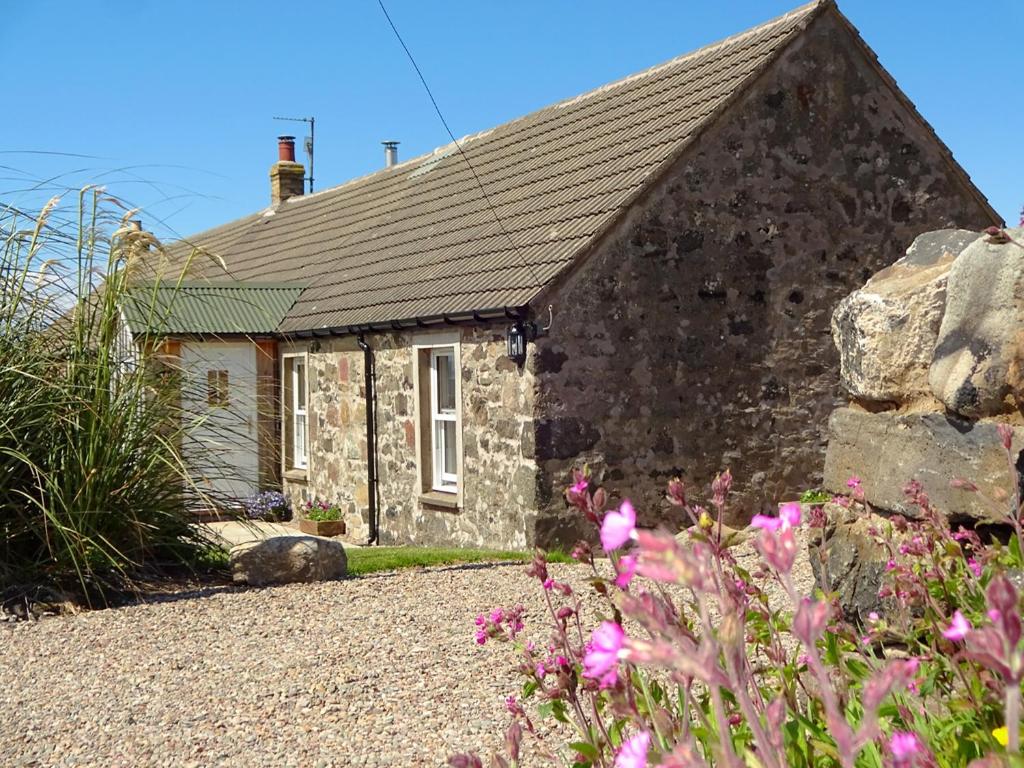 a stone cottage with flowers in front of it at Charlies Cottage in Muasdale