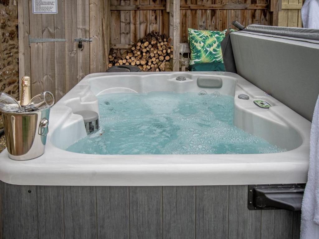 a bath tub with blue water in it at Hall Farm Cottage in Byers Green