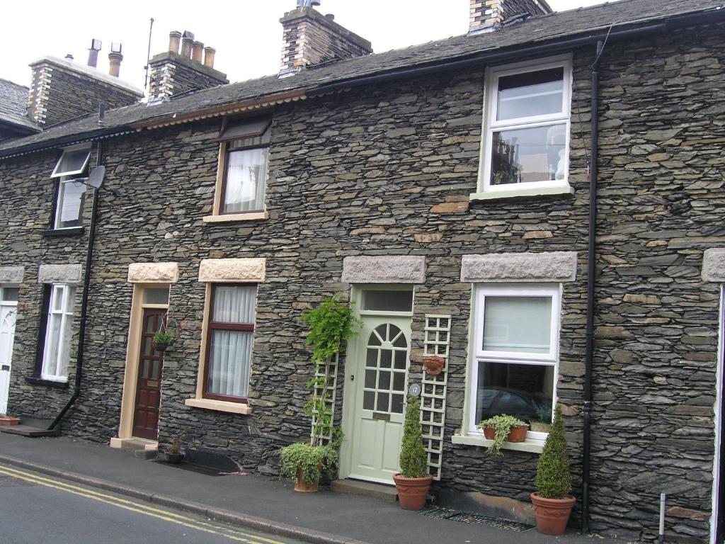 a stone house with a green door and windows at Fireside Cottagewindermere in Windermere