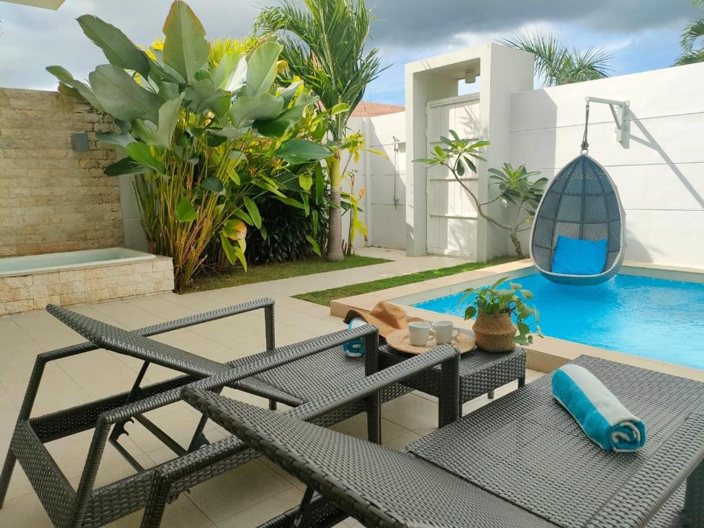 a patio with a table and chairs next to a swimming pool at Pineale Villas, Resort and Spa in Panglao