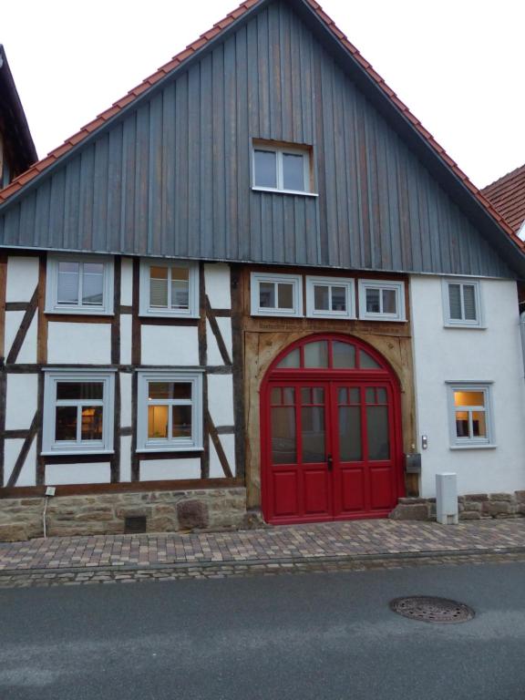 ein Haus mit einer roten Tür auf einer Straße in der Unterkunft Ferienwohnung Schindewolf in Grebenstein