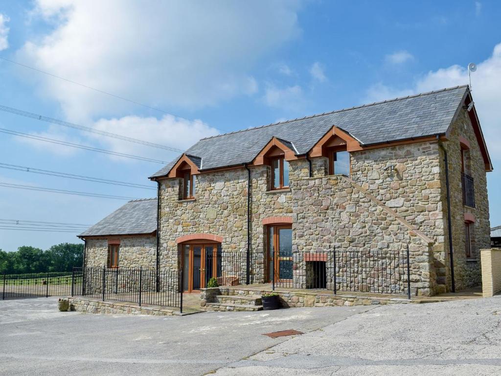 a large stone building with a metal roof at West Rose Barn in Pendine