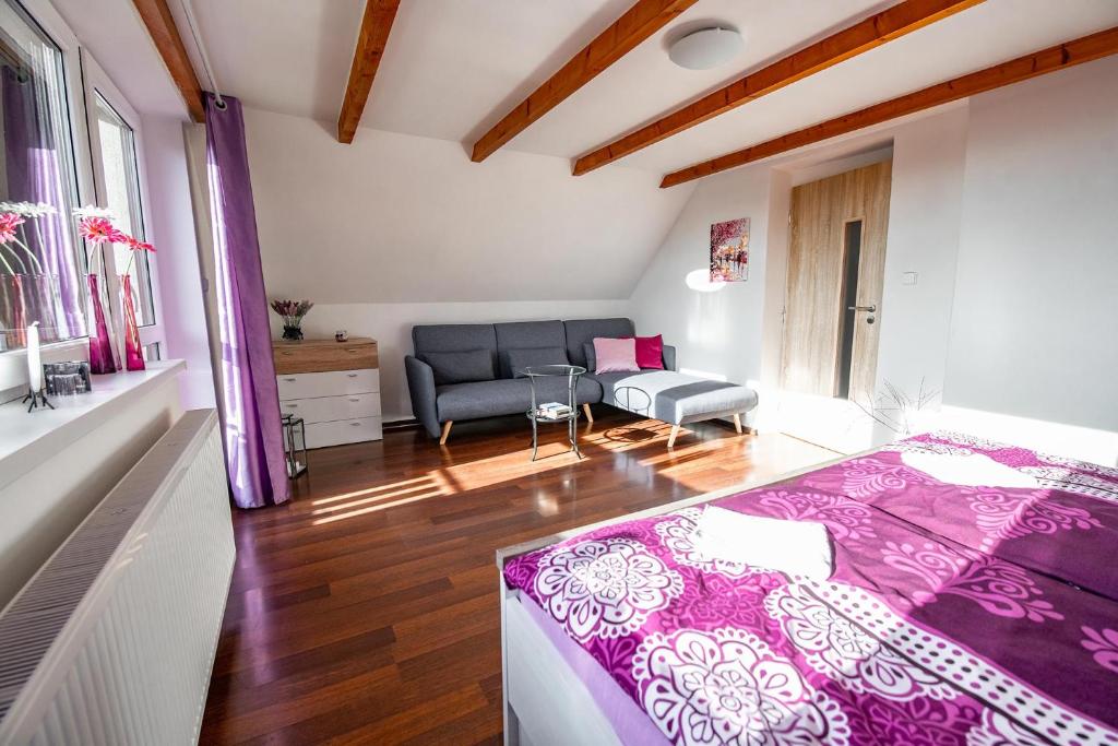 a bedroom with a purple bed and a couch at Chata73 in Nový Hrádek