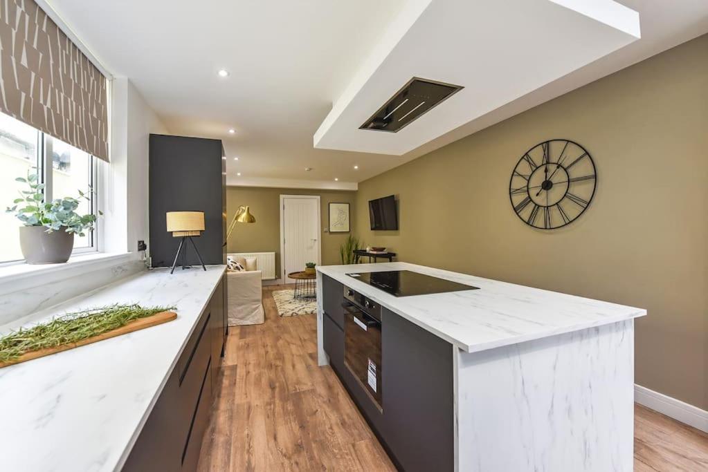 a large kitchen with a white counter and a clock at Modern Two Bed with En-Suites and Private Parking in Cardiff