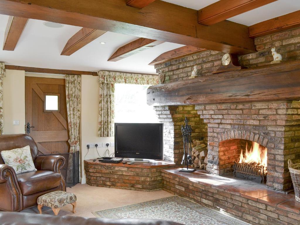 a living room with a fireplace and a television at Walled Garden Lodge in Ryhill