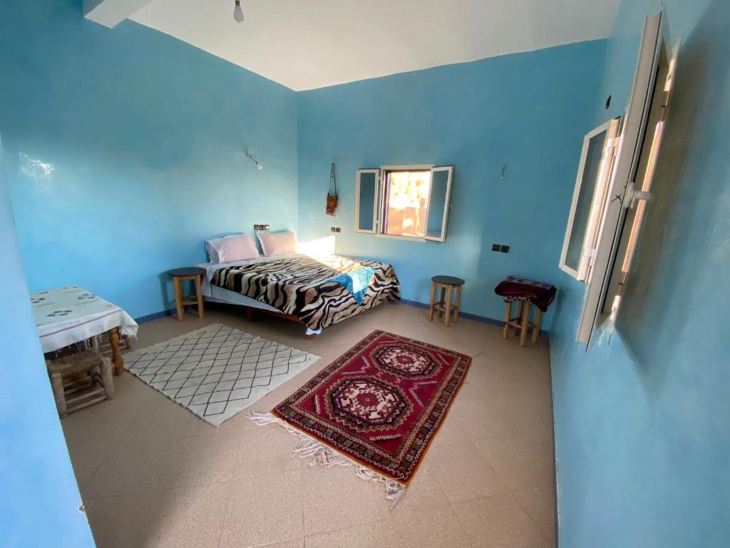 1 dormitorio con cama, mesa y alfombra en jardin du desert, en Mhamid