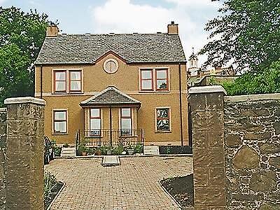 a large house with a stone wall and a gate at 5 Milnamair in Montrose