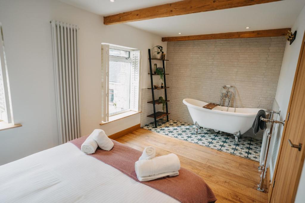 a bedroom with a tub and a bed with towels at The Little Cottage by Truabode Holiday Lets & Short Lets Newquay - Parking, Wifi & Pet Friendly in Newquay