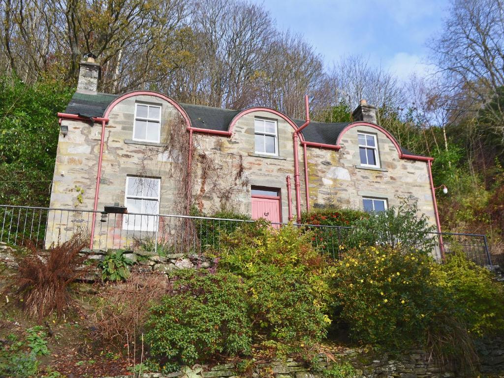 an old stone house with a red door at Garden Cottage in Weem