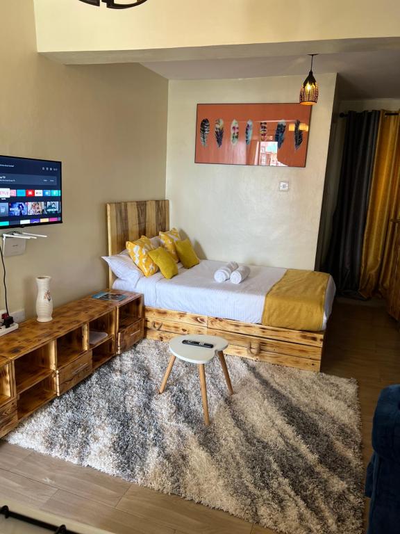 a bedroom with two beds and a table at Ruby Modern Homes Studio-Imara Daima,Behind Imaara Mall-JKIA-Horizon in Nairobi