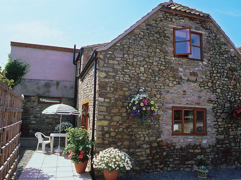 een stenen gebouw met een tafel en een paraplu bij Honey Acre Cottage - E2379 in Banwell
