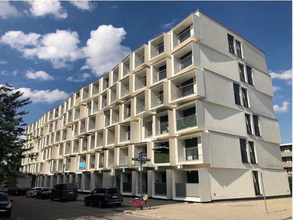 a white building with cars parked in front of it at Myroom Business Apartment Nähe Messe München in Munich