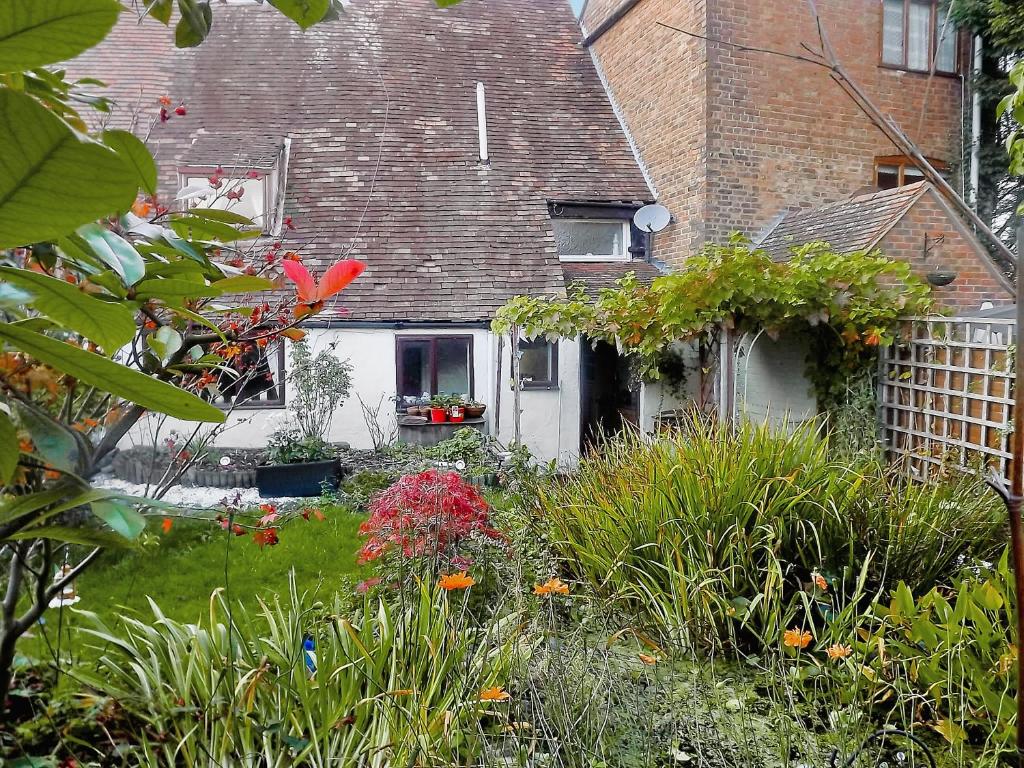 a house with a garden with flowers in the yard at The Hideaway Cottage in Gloucester