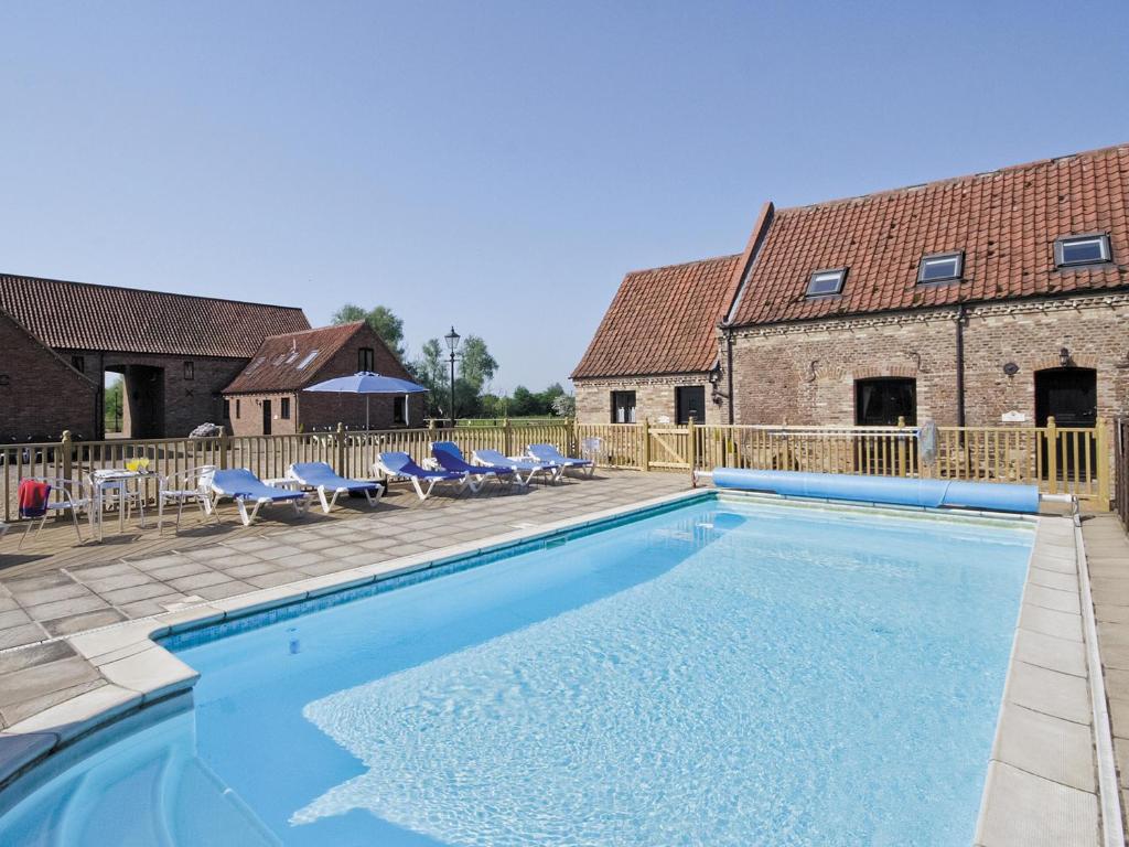 uma piscina com cadeiras e um edifício em Purlin Barn - E3867 em Runcton Holme