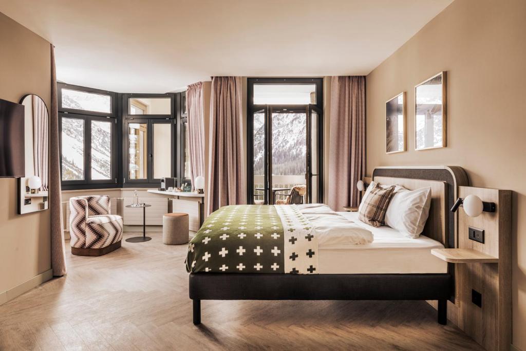 a bedroom with a bed in a room with windows at Faern Arosa Altein in Arosa