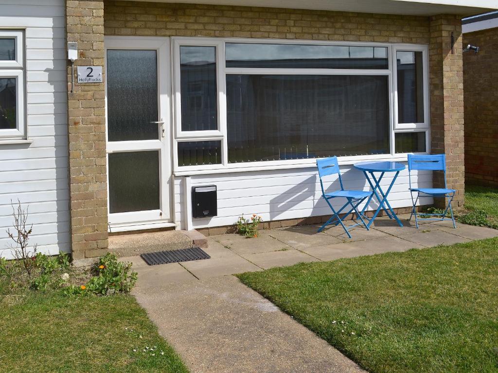 two blue chairs and a table in front of a house at Hollyhocks in Walcott