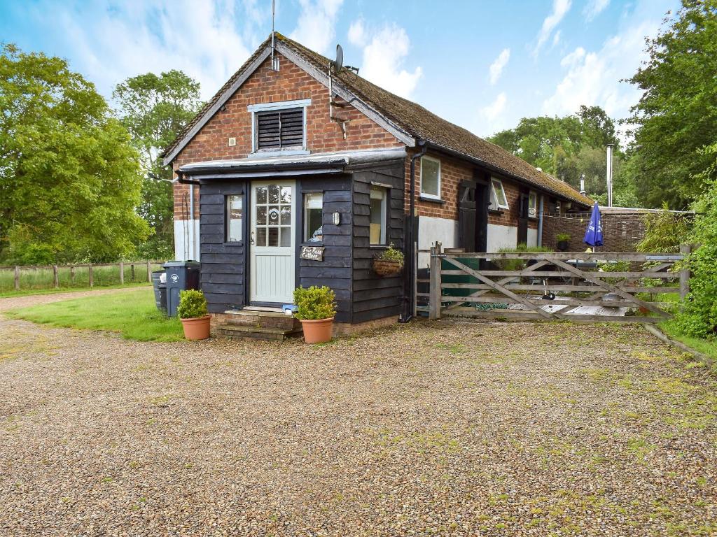 una pequeña casa con una puerta y una valla en Evie Rose Cottage, en Elsenham