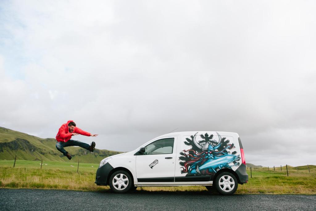 Un homme saute du côté d'une camionnette dans l'établissement KúKú Campers - Campervans, à Keflavík